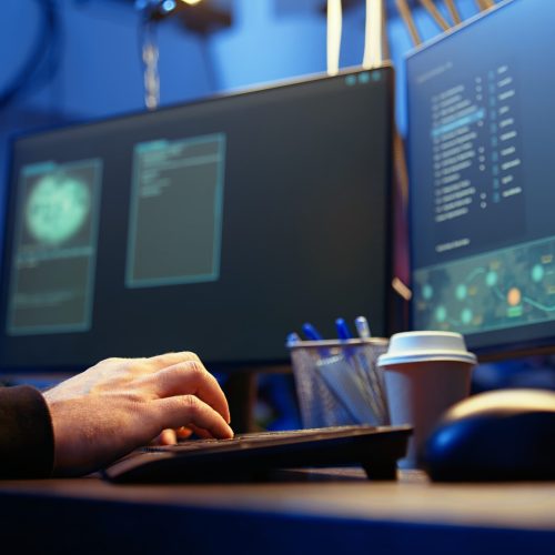 Hackers typing fast on keyboard in graffiti painted hideout, rushing to finish developing spyware software, using it to gather data from users computers without their knowledge, camera A close up